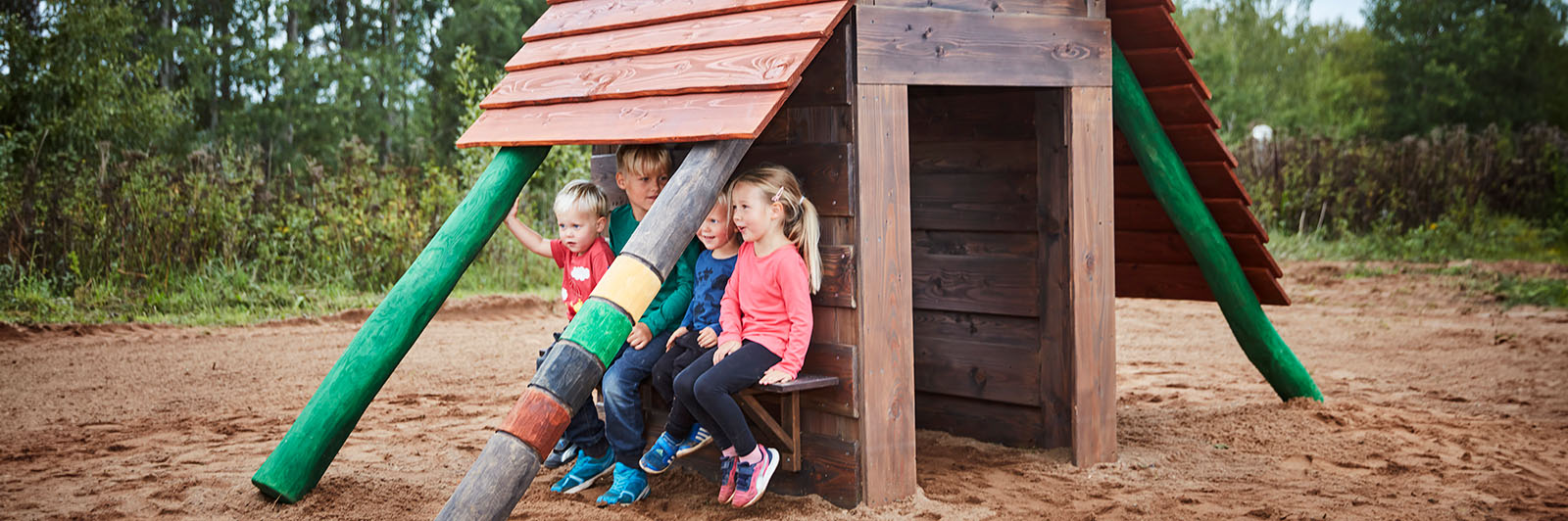 Kinder spielen in einem Spielhaus aus Holz.